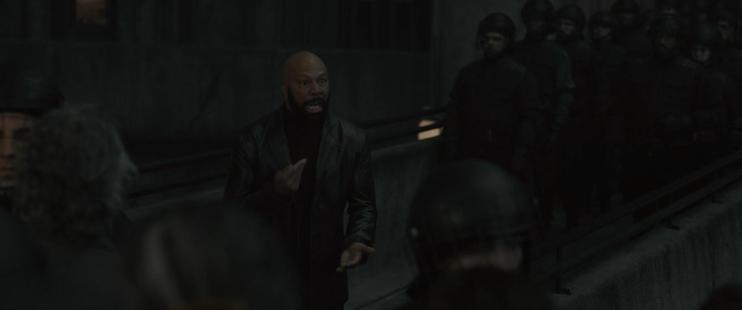 A scene from the Silo TV series where the head enforcer for the people in power rallies citizens to turn on themselves, while tricking them into thinking that they are actually defending themselves.