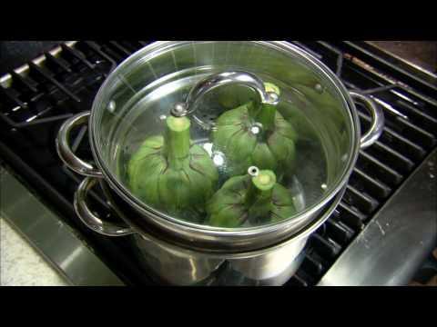 An image of 3 uncooked artichokes placed stem side up, inside the assembled steaming tray and cooking pot. The lid is attached to the pot and artichokes are ready for steaming.