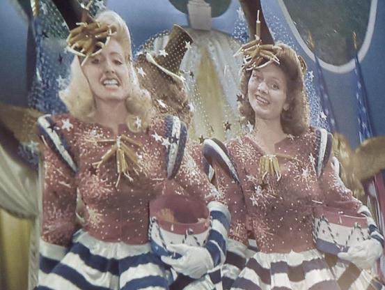 Two young women in patriotic chorus costumes, with striped bouffant skirts, in HOLIDAY INN