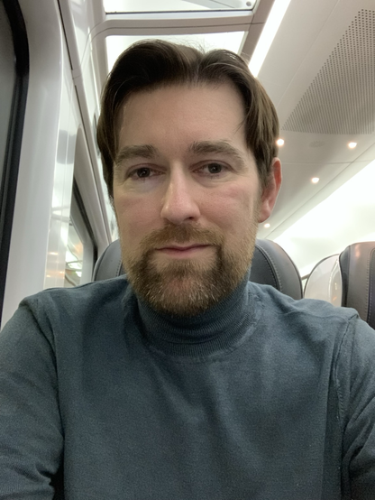 Keith on the train wearing a green turtleneck sweater