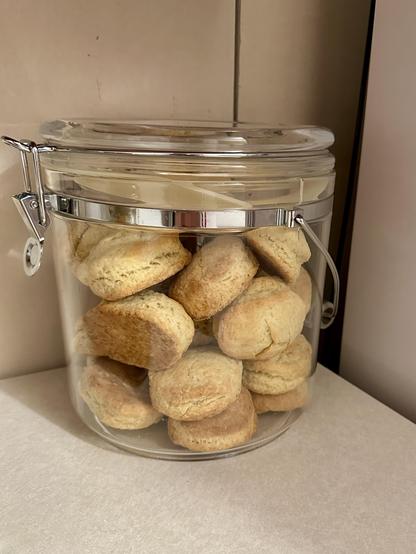 A clear jar full of freshly-baked round cream scones. They look like homemade biscuits (American biscuits, not British biscuits, which everyone knows are really cookies). 