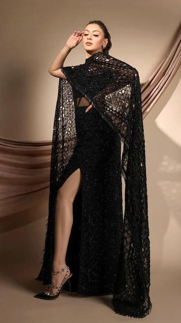 Elegance meets drama in Hansika Motwani’s black gown outfit. Her cape adds a touch of flair, making this look a trendsetter for modern red carpet appearances.
