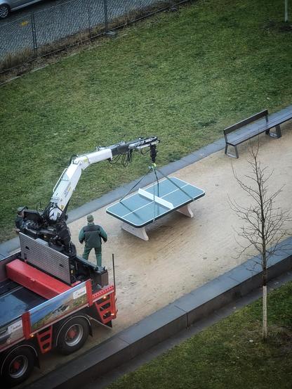 In the reading garden of the university library, a table tennis table is set up with a crane next to the lawn and seating.