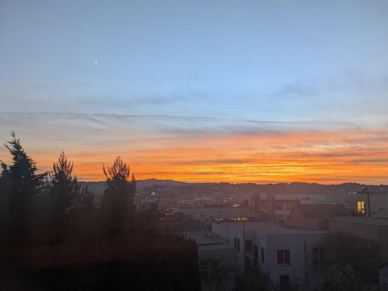 Photograph of the sunset over San Francisco Bayview. Toward the horizon the colors are yellow, orange, and coral, fading into blues as you look up. There are some wispy amethyst-hued clouds. CC BY-SA Kate Zimmerman.