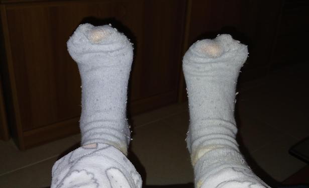 Plano de pies con calcetines celestes viejos. Los dedos gordos se transparentan.