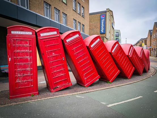 Artwork of red telephone boxes falling like dominoes 