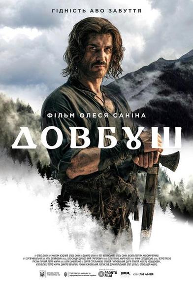 Ein Mann in einem mittelalterlichen Outfit und mit einer Axt steht in der Mitte des Bildes. Im Hintergrund ist eine Landschaft aus Bergen zu sehen. In der Mitte steht der ukrainische Titel des Films, der übersetzt „DOVBUSH“ lautet.