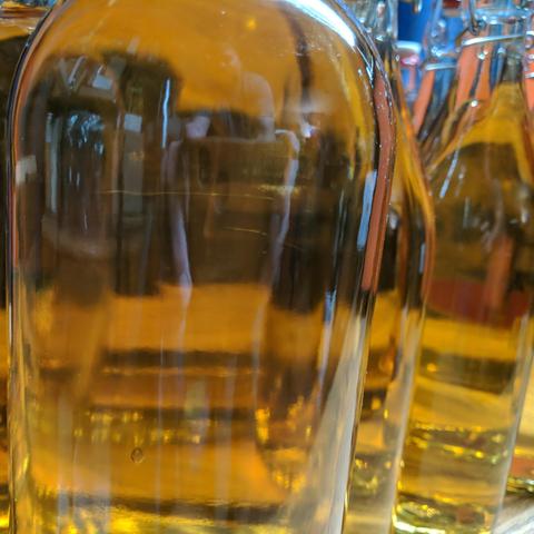 A square cropped closeup photo of one of the 1.5 liter bottles showing the clarity. There are other bottles visible on the right side of the photo. There are reflections in the glass of the bottles that have no labels.