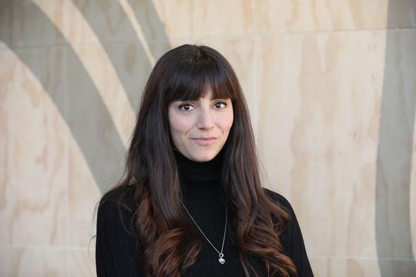A photo of Isabella wearing a black top and a silver necklace.