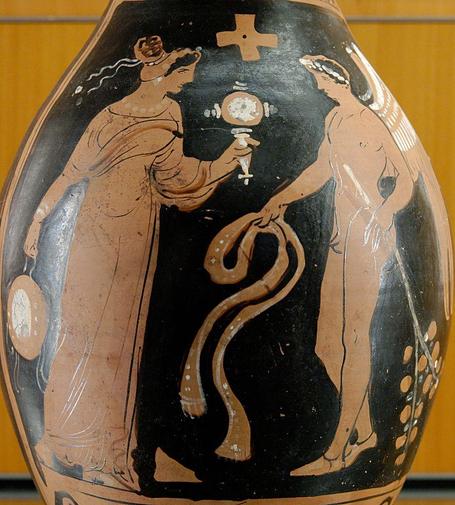 Winged genius (right) facing a woman (left) with a tambourine and mirror, from southern Italy, about 320 BCE. Source: Wikimedia Commonsꜛ (license: CC BY 2.5)