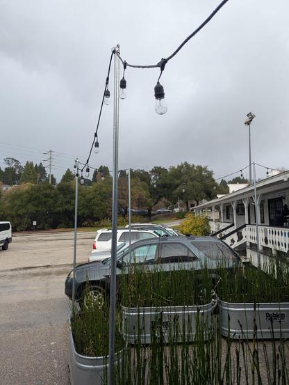 A parking lot with a tornado going by behind some trees in the distance