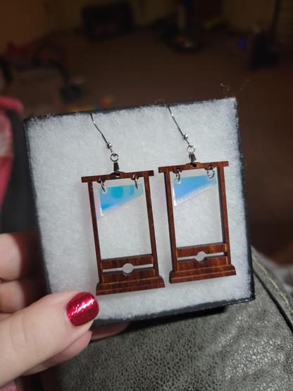 A picture of earrings shaped like guillotines, made of wood and acrylic.