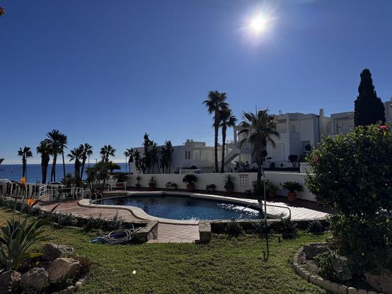 Outdoor swimming pool in a Spanish residencial complex with a bright blue sky and strong sunshine