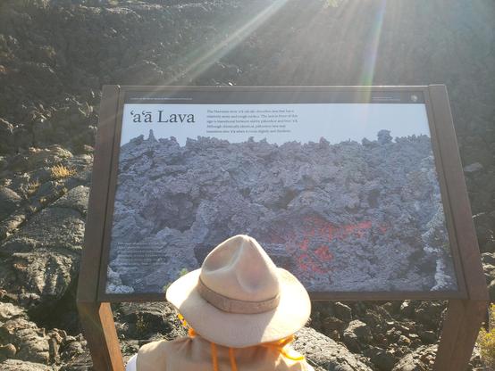 Ranger Sarah learns about a'a lava. In Hawaiian, a'a means "hard on the feet." Most lava flows emerge as pahoehoe and somewhere down the slope change into a'a as the lava cools, loses much of its gas, and becomes thicker. As the flow cools, it begins to slow down, moving as a mass of broken rubble.
— at Craters of the Moon NPS.

