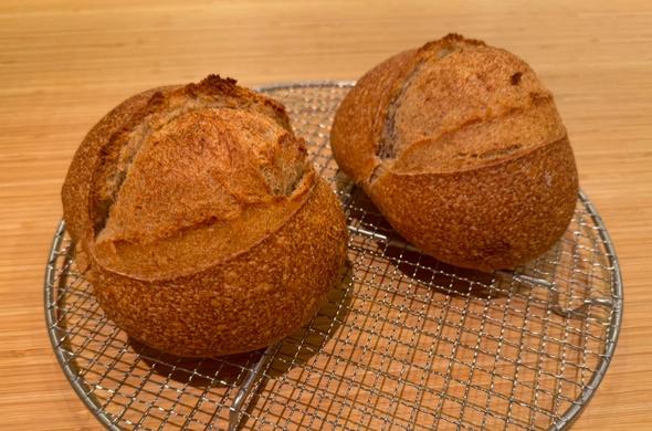 Two round loafs of bread on a cooling rack.