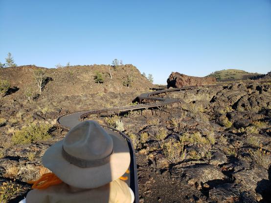 Ranger Sarah hikes through lava known as Blue Dragon Lava. The blue color comes from a thin outer layer of lava that contains titanium magnetite crystals. These abundant crystals reflect the intense blue light.
— at Craters of the Moon NPS.
