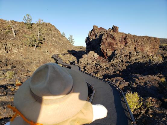 Ranger Sarah nears the end of the trail. Some of the lava is red where the blue lava has been broken and removed. This red coloration occurs because basaltic lava rock is high in iron. Metals such as iron rust when they are in contact with oxygen.
— at Craters of the Moon NPS.
