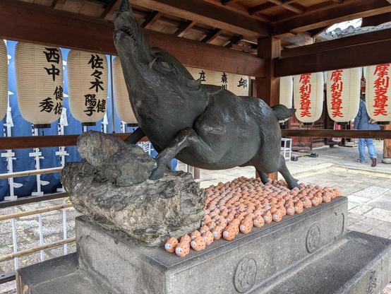 Boar omikuji holders are left beneath a large boar statue at Zenkyo-an.