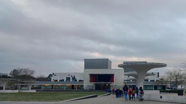 A group of schoolchildren with their teachers on their way to the Staatstheater Darmstadt to see the opera „Der kleine Prinz“, the German language version of Pierangelo Valtinoni’s opera «Il piccolo principe». In the background the white façade and grey towers of the Staatstheater, in the left the still green gras of the Georg-Büchner-Platz terraces. Photo: Stefan Romero Grieser, CC BY-SA