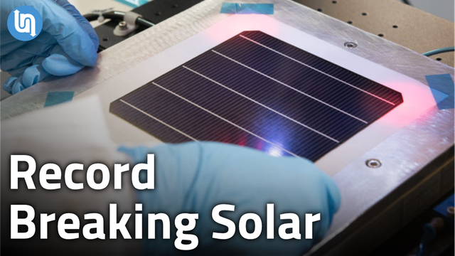 A pair of blue-gloved hands moving an Oxford PV perovskite solar cell