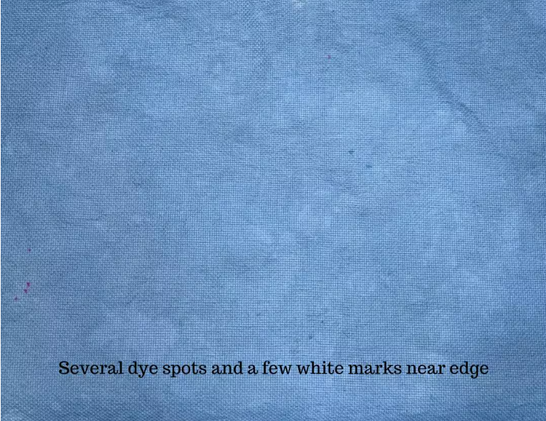 A cool blue fabric with some darker blue speckles and some purple-pink speckles. The text on the bottom says "several dye spots and a few white marks near edge.)