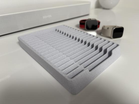 A close-up of an empty gray watch band organizer tray with clean, evenly spaced grooves designed to hold multiple watch straps. 