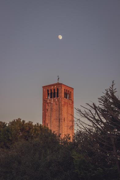 Se puede ver la torre de la basílica de Santa María de Asunta de Torcello casi en hora azul y sobre ella la luna casi llena.