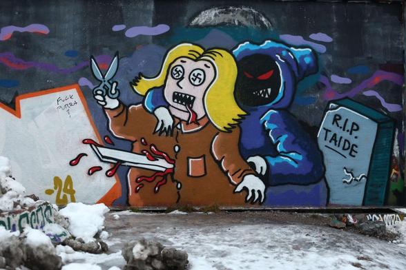 Hakaristisilmäinen naishahmo saksien kanssa saa katanasta. Graffiti.