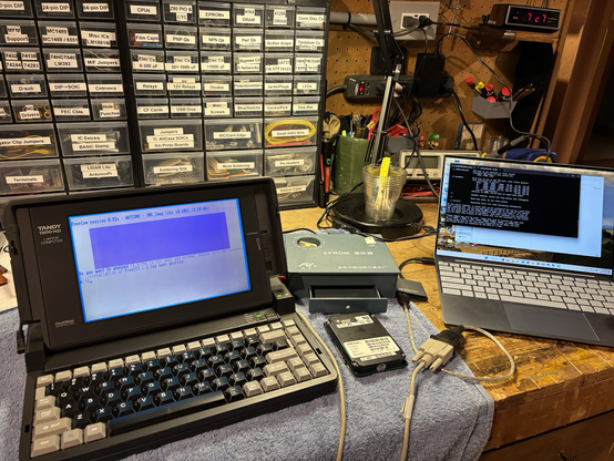 Tandy 1500 HD laptop connected to a modern Dell laptop via serial cable, with the 1500 booted to FreeDOS.