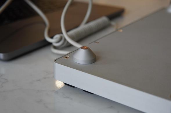 A closeup of a cone shaped riser, or “foot”, of the aforementioned silver keyboard.