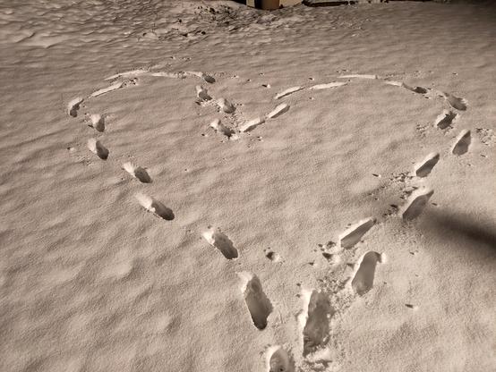 foot steps in snow forming a heart shape
