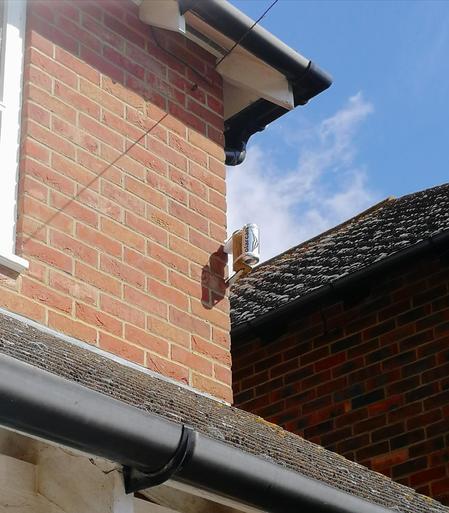 Corner of a house with a bracket attached which holds the solarcan itself.