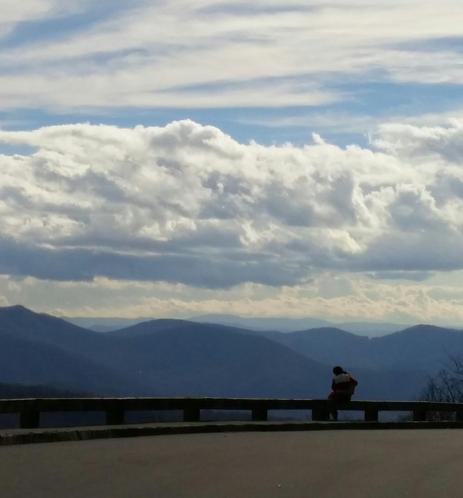 Blue ridge parkway Vista with mountains and clouds with someone sitting on the rail looking out