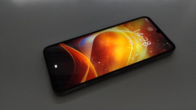 A Jolla C2 showing Sailfish OS running with one of the inbuilt ambiences (called "Flare", it looks like waves and fire and sparks in reds and oranges and yellows).
