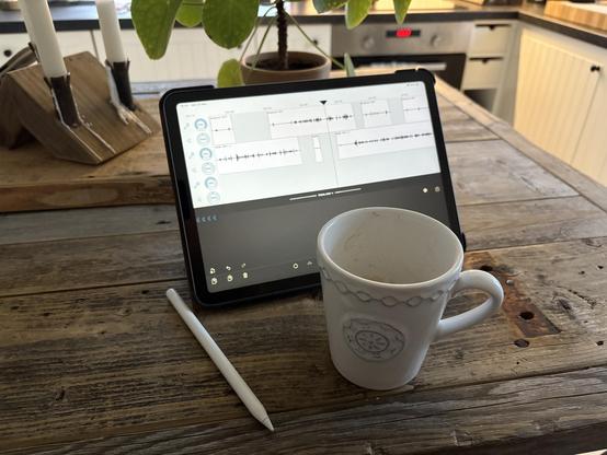 En iPad med ett ljudredigeringsprogram igång på skärmen och en kopp kaffe