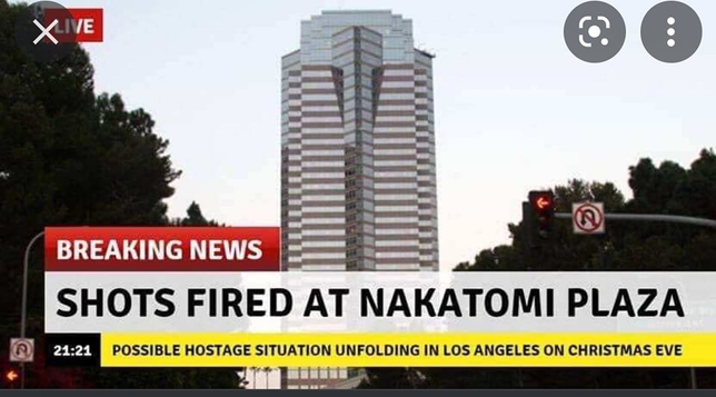 **TL;DR:** A mock breaking news graphic reports a hostage situation at Nakatomi Plaza from the movie *Die Hard*.
The image shows the fictional Nakatomi Plaza, a tall glass-and-steel skyscraper, with a breaking news banner at the bottom. The red banner reads "BREAKING NEWS," followed by "SHOTS FIRED AT NAKATOMI PLAZA" in bold text. A yellow sub-banner adds: "Possible hostage situation unfolding in Los Angeles on Christmas Eve." The time stamp in the corner reads "21:21." The building is surrounded by trees and traffic lights in a twilight setting.
This is a reference to *Die Hard* (1988), where the Nakatomi Plaza is the central location of the film's plot involving a hostage crisis.