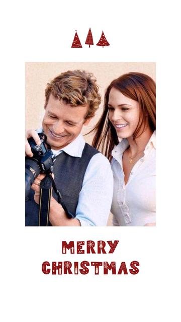 Actors Simon Baker and Amanda Righetti check out pictures on the digital camera Simon is holding. The sentiment of the post is Merry Christmas.