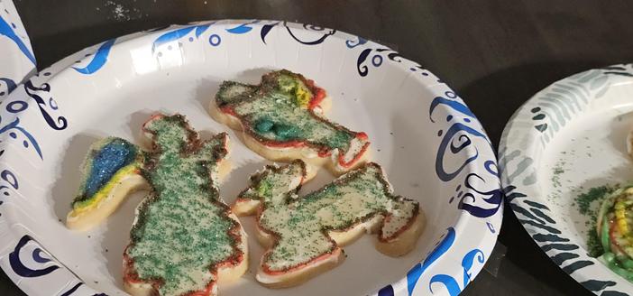 3 sugar cookies decorated for Christmas. An angel, a reindeer, and a santa.