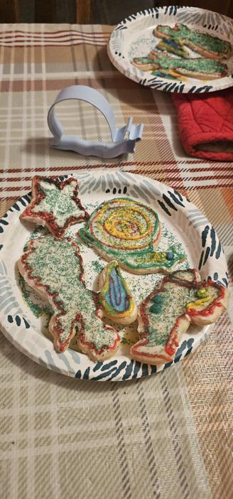 4 of the cookies on a plate together, Christmas themed shapes with one snail. A snail cookie cutter is in the background
