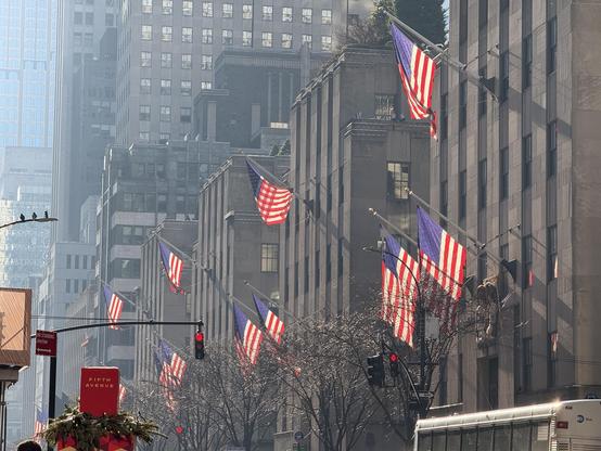 A view down fifth Ave in NYC looking at part of Rockefeller Center festooned in American flags. 