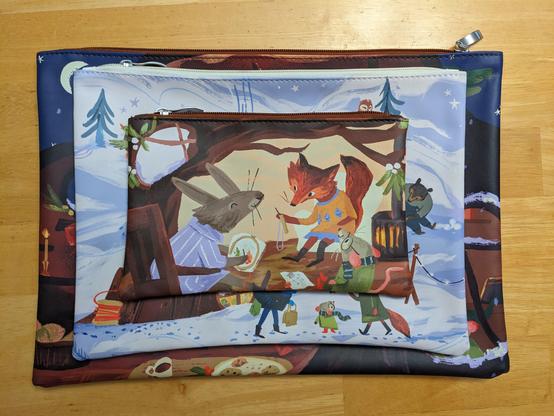 A stack of three different sized project bags. The top on is a scene of fox, rabbit, and mouse crafting together.