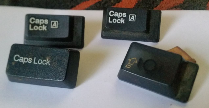 four caps-lock keys detached from their respective keyboards