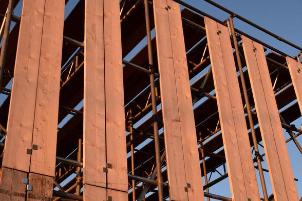 Some vertically mounted scaffolding boards lit with light from a sunset.