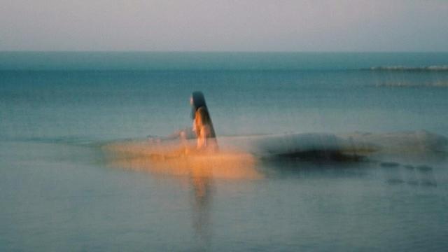 Blurry image of person sitting on sand bar.