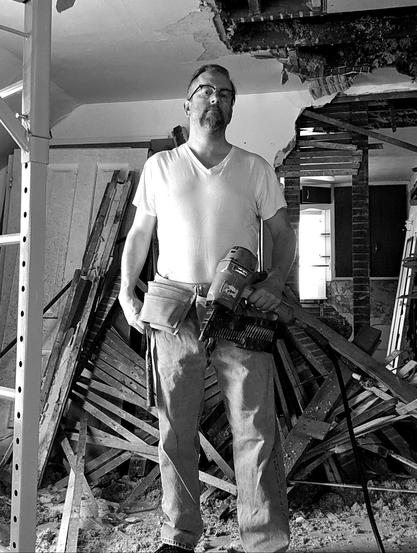 Selfie, I'm holding a coil framing air nail gun and wearing a toolbelt with a steel shaft framing hammer in the hammer loop, while standing on the 2nd floor of a house I'm renovating 