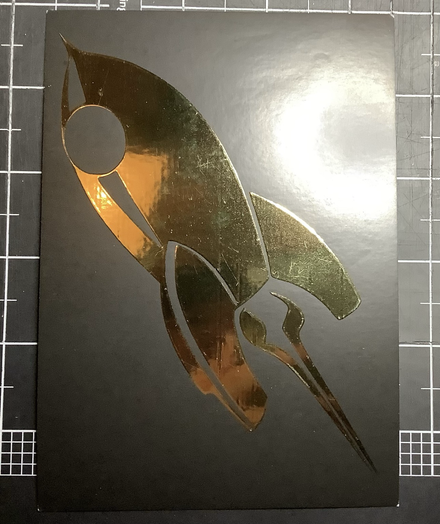 Postkarte mit einer goldenen Rakete auf schwarzem Hintergrund 