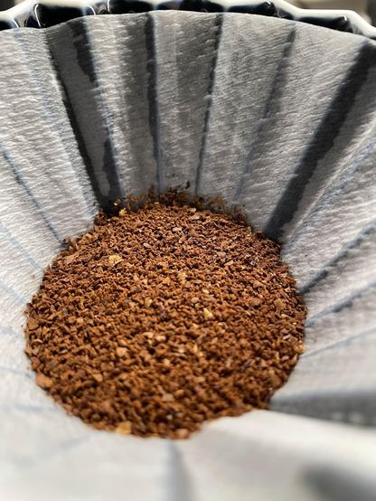 A close up of ground coffee beans sitting in a paper filter.