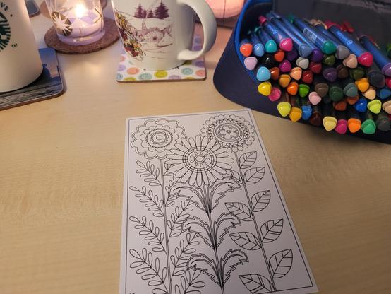 Ausmalbild mit Blumen, an der Seite liegen Stifte und Üben stehen Tassen. 