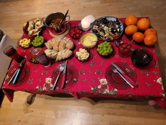Tisch mit Essen, Brötchen, Topf mit chilli con carne, Tomaten, Käse, Weintrauben, Baguettes, Gurke