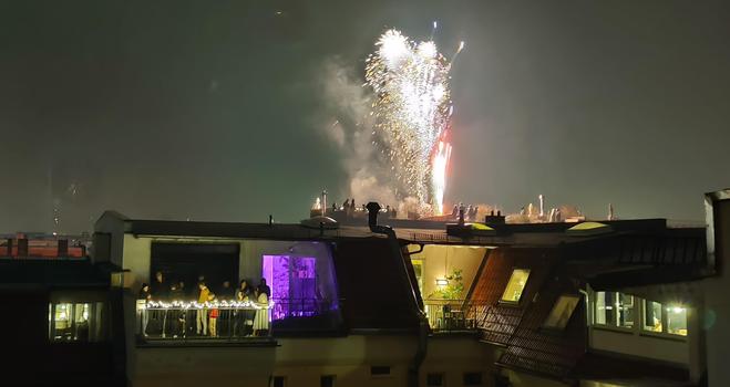Fireworks and a lot of people on a balcony lighting fireworks